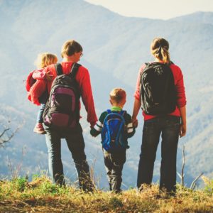 Photo d'un couple avec deux enfants de dos en tenue de randonneur en train de regarder le paysage
