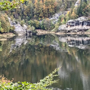 Vue sur un lac entouré de roche et de sapins dans le Doubs